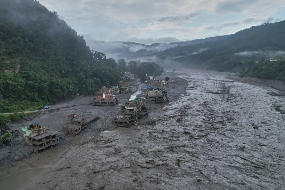 Aerial view of a Nepali river town buried in flood silt with buildings partly swept away