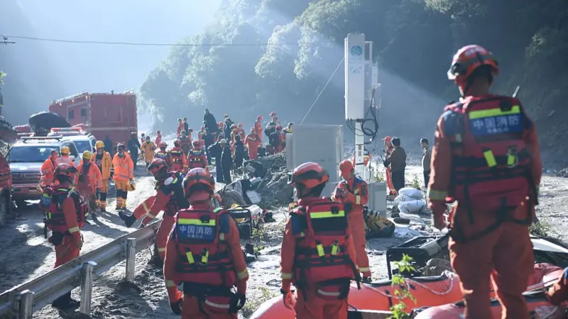 Rescue teams in orange gear staging along a mud-covered road